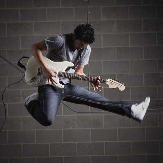 Man jumping in air while playing guitar. Photo : Mike Kemp