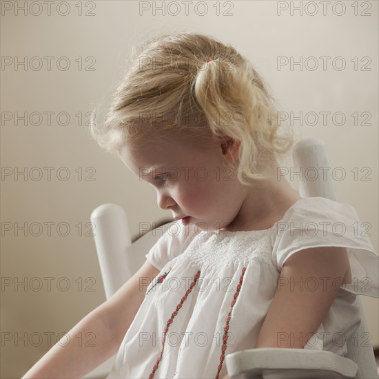 Sad young girl sitting in rocking chair. Photo : Mike Kemp