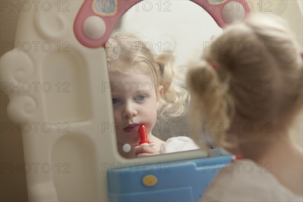 Young girl putting on lipstick. Photo : Mike Kemp