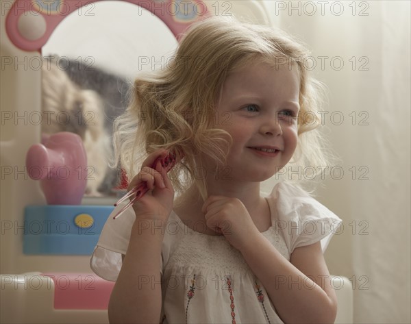 Young girl combing her hair. Photo : Mike Kemp