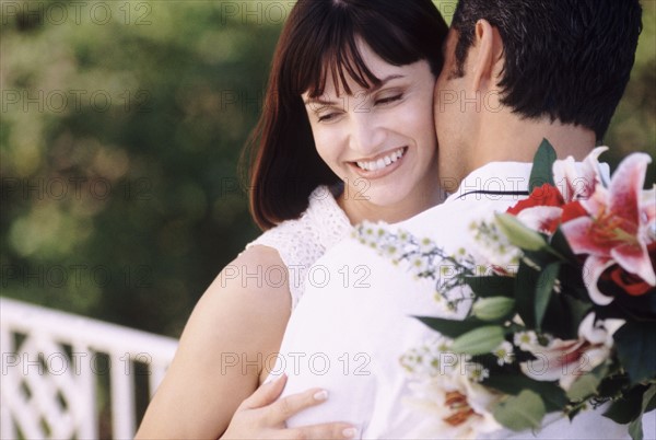 Man kissing woman as he holds flowers behind his back. Photo : Rob Lewine