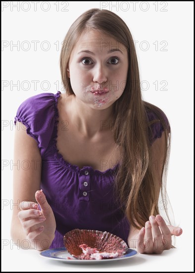 Woman with a cupcake stuffed in her mouth. Photo : Mike Kemp