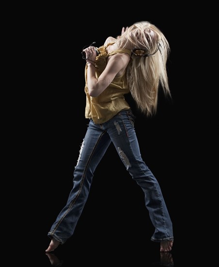 Blond woman dancing while listening to music on Mp3 player. Photo : Mike Kemp