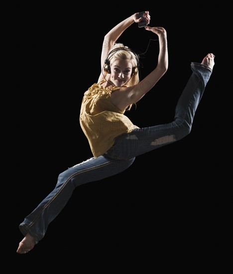 Blond woman dancing while listening to music on Mp3 player. Photo : Mike Kemp