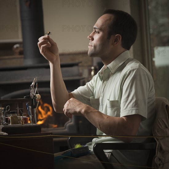 Man looking at fly fishing hook. Photo : Mike Kemp