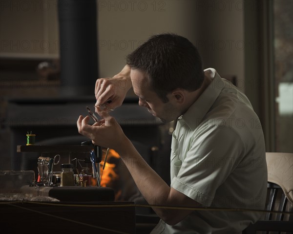 Man repairing fly fishing hook. Photo : Mike Kemp