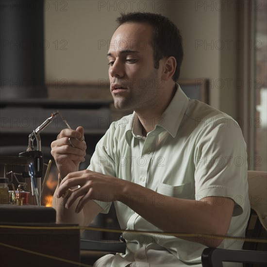 Man repairing fly fishing hook. Photo : Mike Kemp