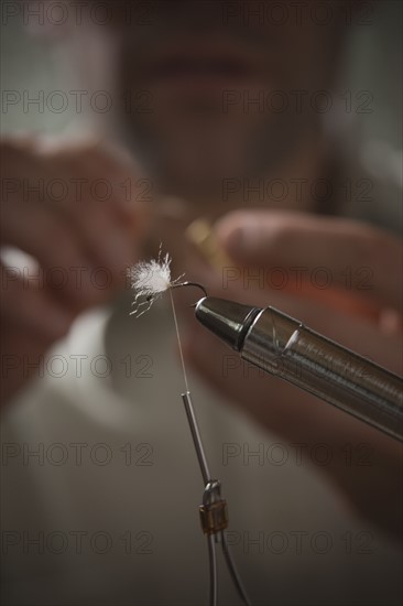 Man repairing fly fishing hook. Photo : Mike Kemp