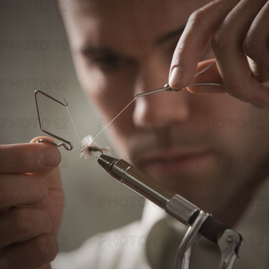 Man repairing fly fishing hook. Photo : Mike Kemp