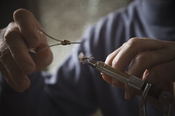 Hands working on fly fishing hook. Photo : Mike Kemp