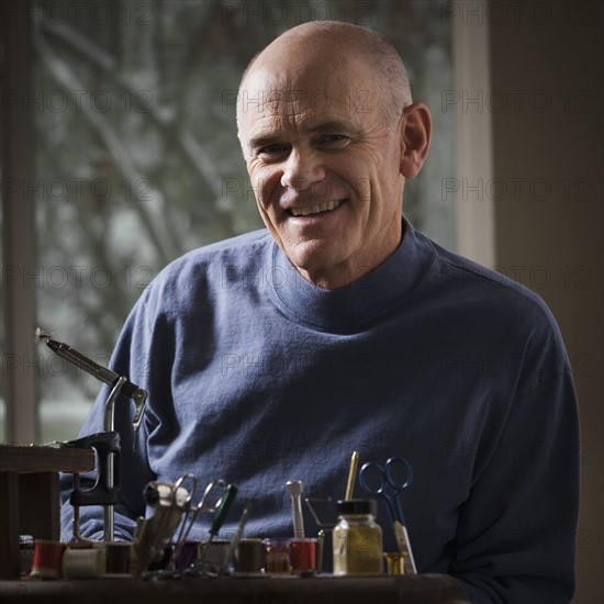 Man sitting behind fishing gear repair equipment. Photo : Mike Kemp