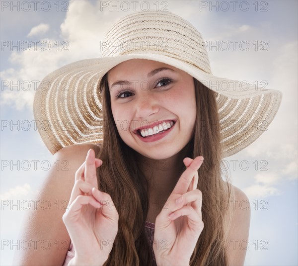 Woman wearing a straw hat and crossing her fingers. Photo : Mike Kemp