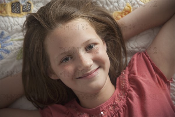 Young girl relaxing on her bed. Photo : Mike Kemp