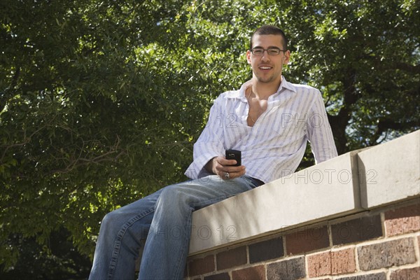 Teenage boy sitting on brick wall. Photo : Stewart Cohen