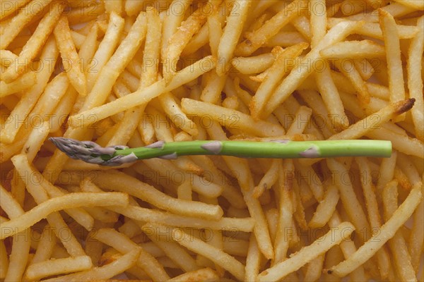 Asparagus spear on top of a pile of French fries. Photo : Mike Kemp