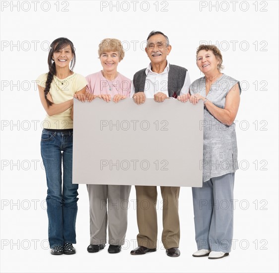 Four people holding a blank poster. Photo : momentimages