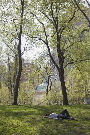 Man lying on the grass in Central Park. Photo : David Engelhardt