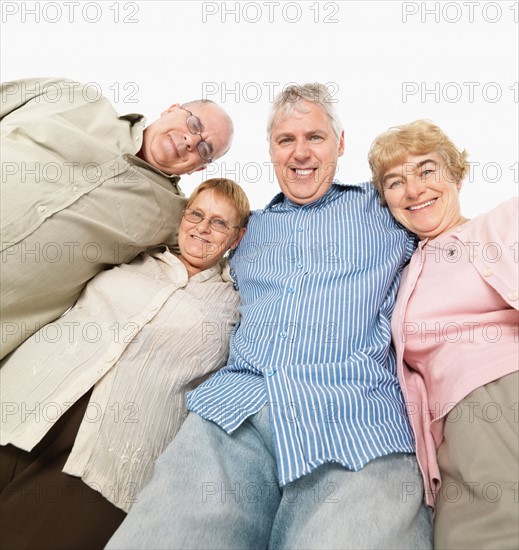 Four friends standing with their arms around each other. Photo : momentimages