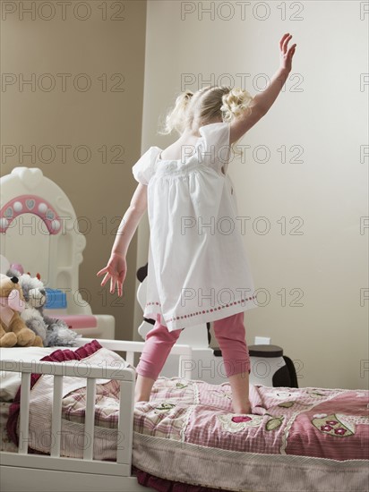 Young girl dancing on her bed. Photo : Mike Kemp