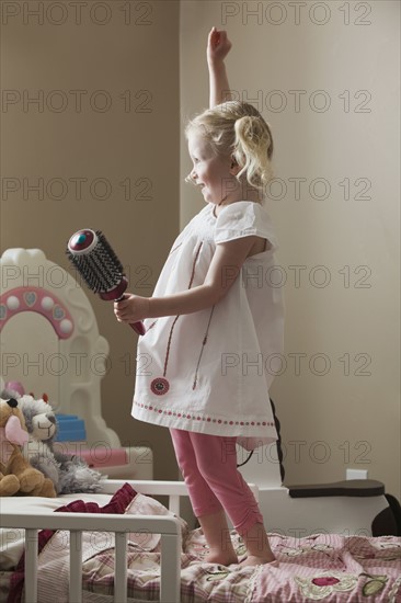 Young girl dancing on her bed. Photo : Mike Kemp