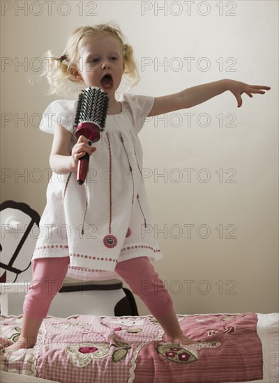 Young girl singing on her bed. Photo : Mike Kemp