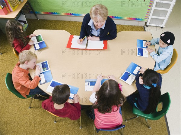 Kindergarten students sitting at table with their teacher.