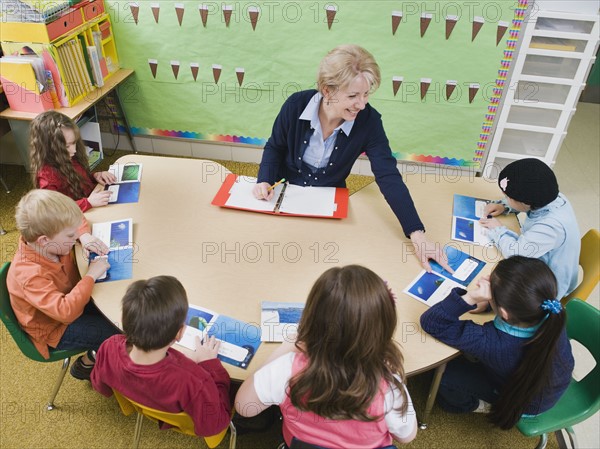 Kindergarten students sitting at table with their teacher.