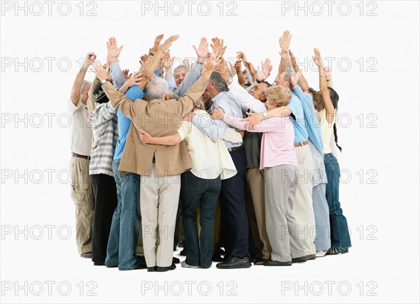 A group of people hugging and raising their arms. Photo : momentimages