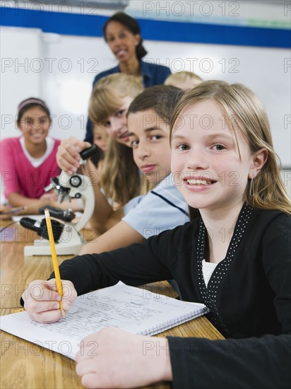 Teacher and elementary students looking at microscope.