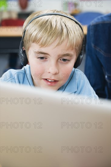 Elementary student wearing headphones in classroom.