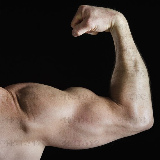 Muscular man flexing his bicep. Photo : Daniel Grill