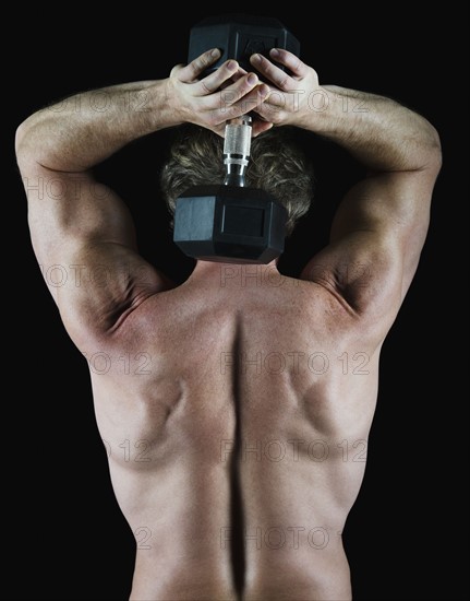 Man lifting free weight behind his head. Photo : Daniel Grill