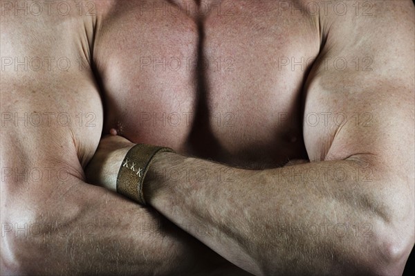Shirtless muscular man with his arms crossed. Photo : Daniel Grill