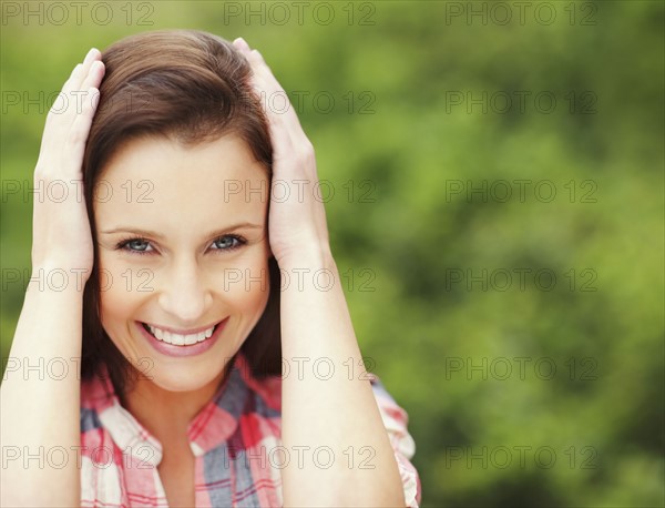 Pretty woman holding her hands against her head. Photo : momentimages