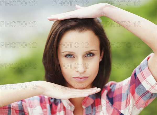 Woman making frame around her head with her hands. Photo : momentimages