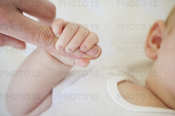 Infant holding onto adult's finger. Photo : Chris Grill