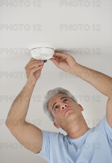 Man changing battery in smoke detector.