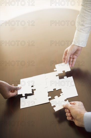 Hands putting puzzle together.