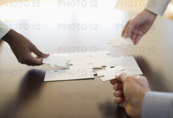 Hands putting puzzle together.