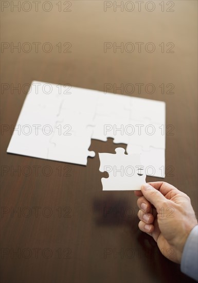 Hand putting last puzzle piece in puzzle.
