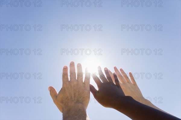 Hands held up in front of sunshine.