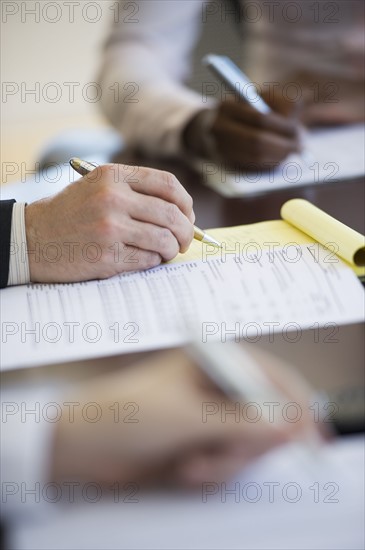 Business people writing notes during business meeting.