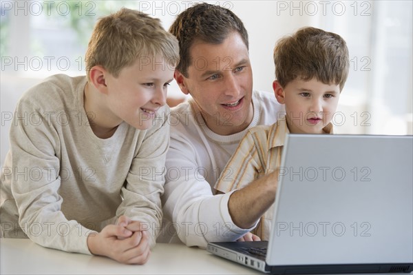 Father and sons looking at laptop.