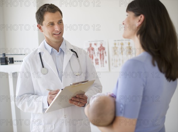 Doctor talking to woman in examination room.