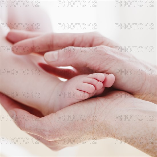 Hands cradling baby's foot. Photo : Jamie Grill