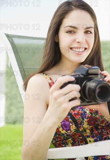 Young woman holding a camera. Photo : Jamie Grill