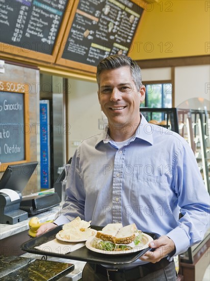 Man carrying sandwich on tray.