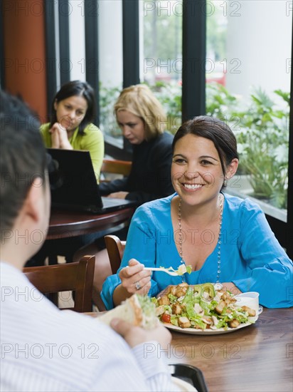 Woman eating salad in restaurant.