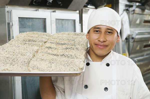 Chef holding tray of bread.