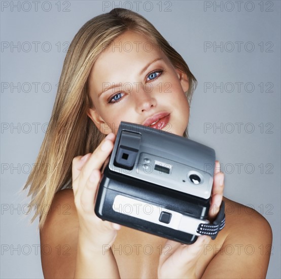 Naked blond woman holding a camera. Photo. momentimages